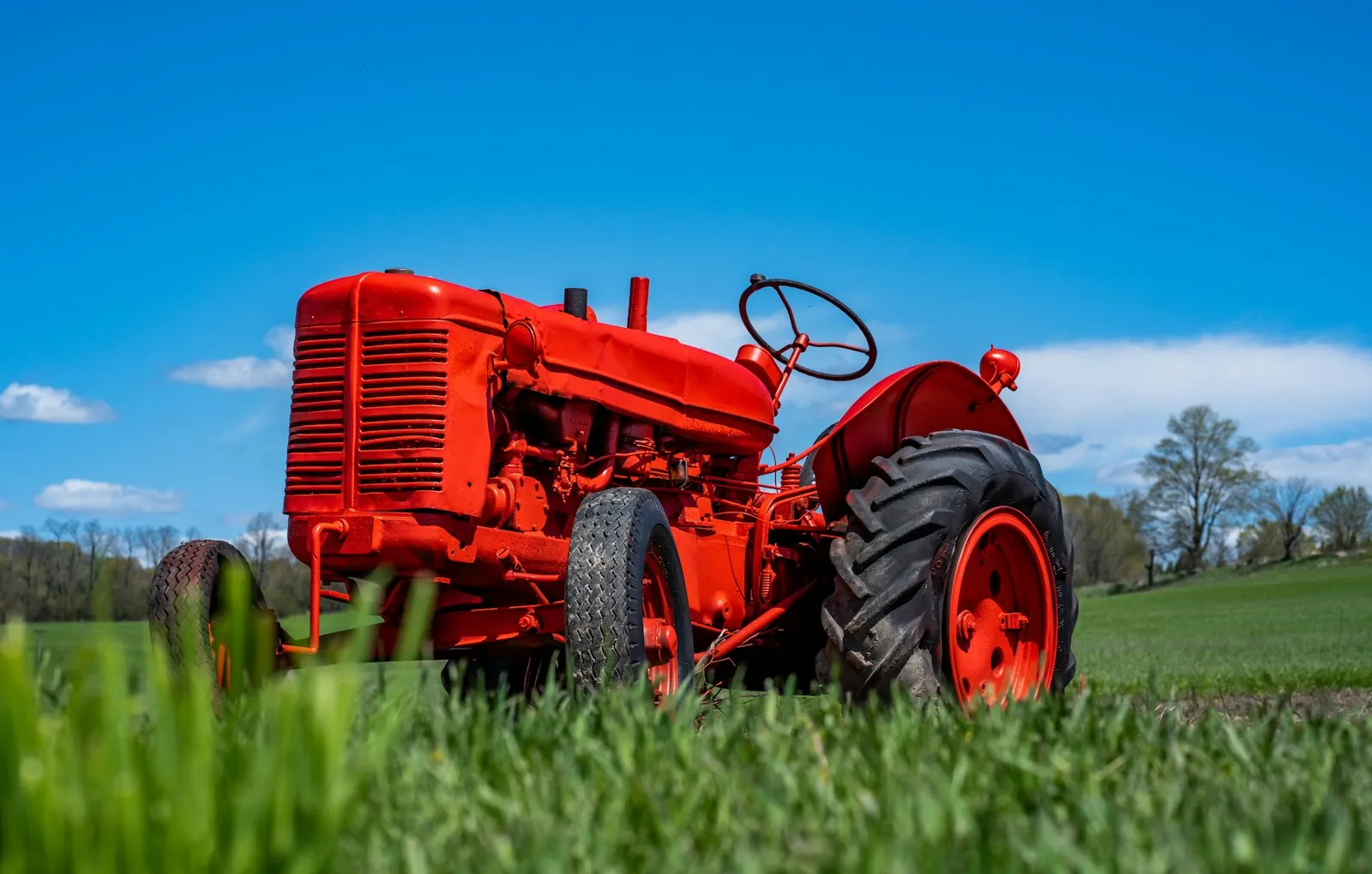 A classic red tractor in a green field